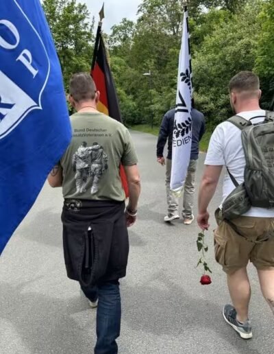 Veteranenwochenende 2024 mit dem 8.Tag der EinsatzVeteranen 29 Männer mit Fahnen laufend auf einer Straße