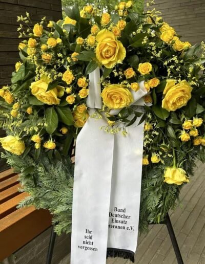Veteranenwochenende 2024 mit dem 8.Tag der EinsatzVeteranen 77 Blumenkranz mit gelden Blumen - Aufschrift Ihr seid nicht vergessen